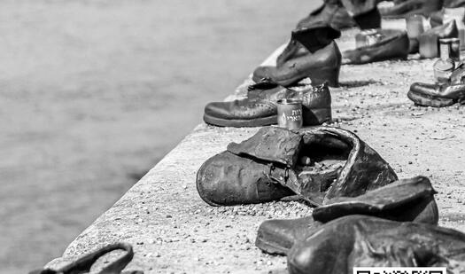 Das Foto ist in schwarzweiß. Auf einer Mauer stehen alte schwarze Schuhe.