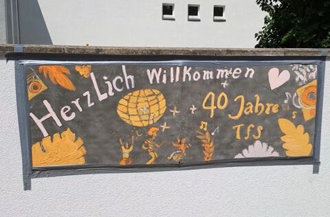 Jubilaeum Tagesfoerderstaette Charlottenburg mit einem Plakat an einer Wand mit Zeichnungen von tanzenenden Menschen und dem Satz Herzlich Willkommen