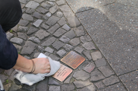 Ehrenamtsaktion im Herbst 2020 mit einer Hand, die mit einem Putzlappen zwei Stolpersteine putz.